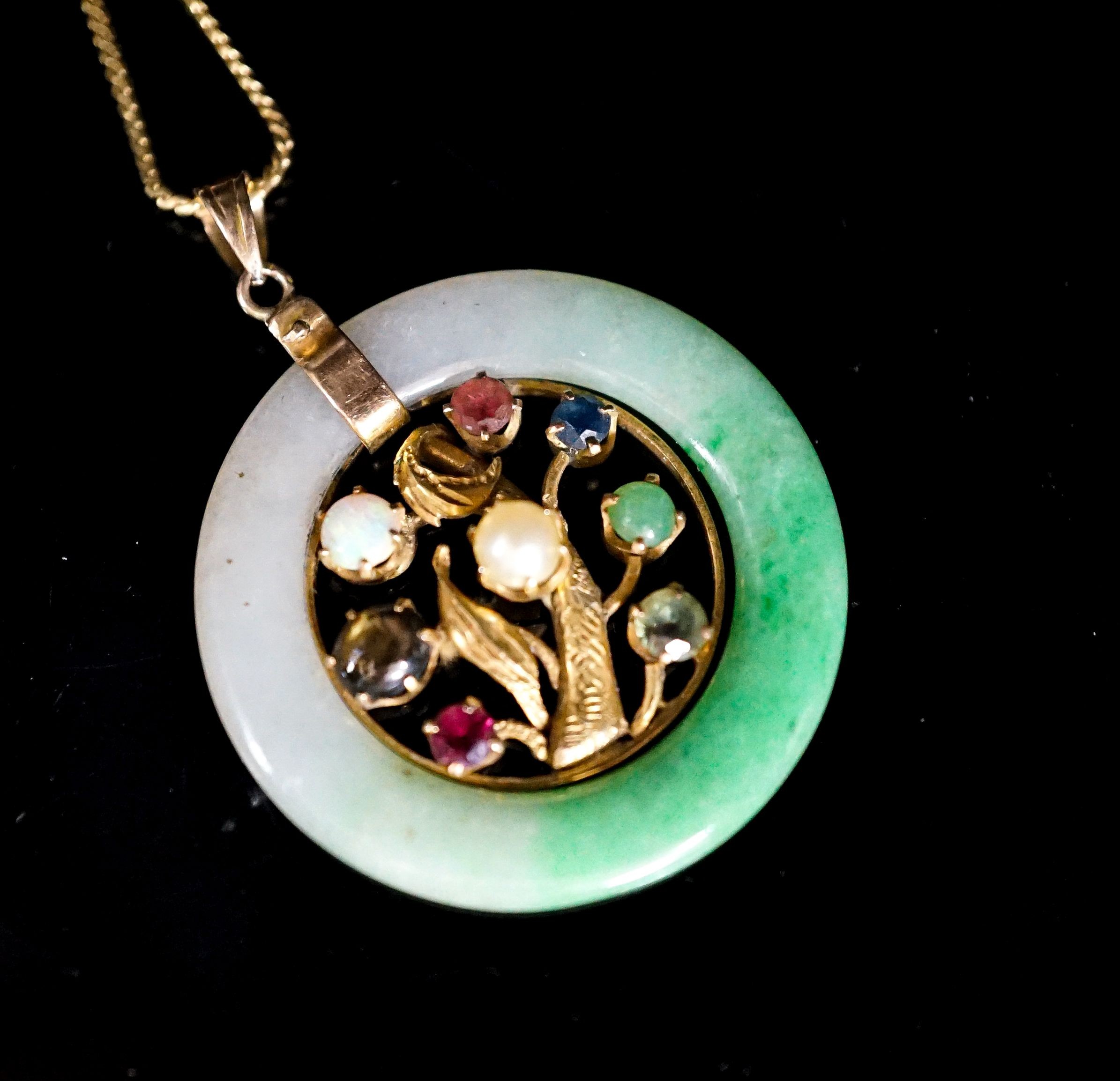 A yellow metal and gem set mounted jade disc pendant, 30mm on s yellow metal fine link chain, gross weight 9.2 grams.